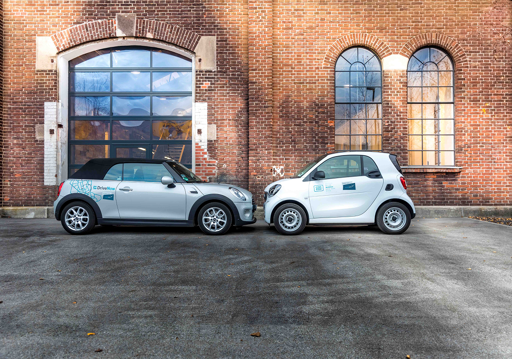 A DriveNow MINI Cabrio and a car2go Smart parked side by side outside a brick warehouse